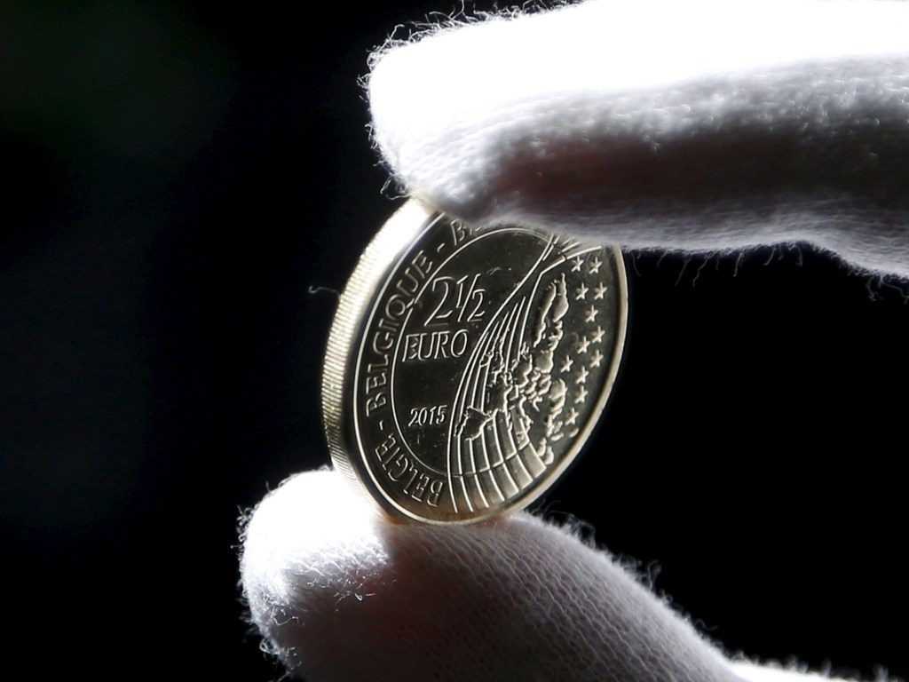 Trabalhador exibe moeda de 2,5 euros lançada para comemorar o bicentenário da batalha de Waterloo