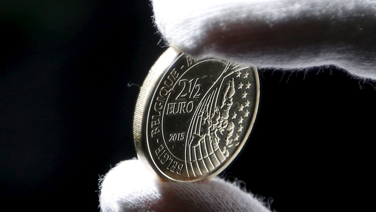 Trabalhador exibe moeda de 2,5 euros lançada para comemorar o bicentenário da batalha de Waterloo