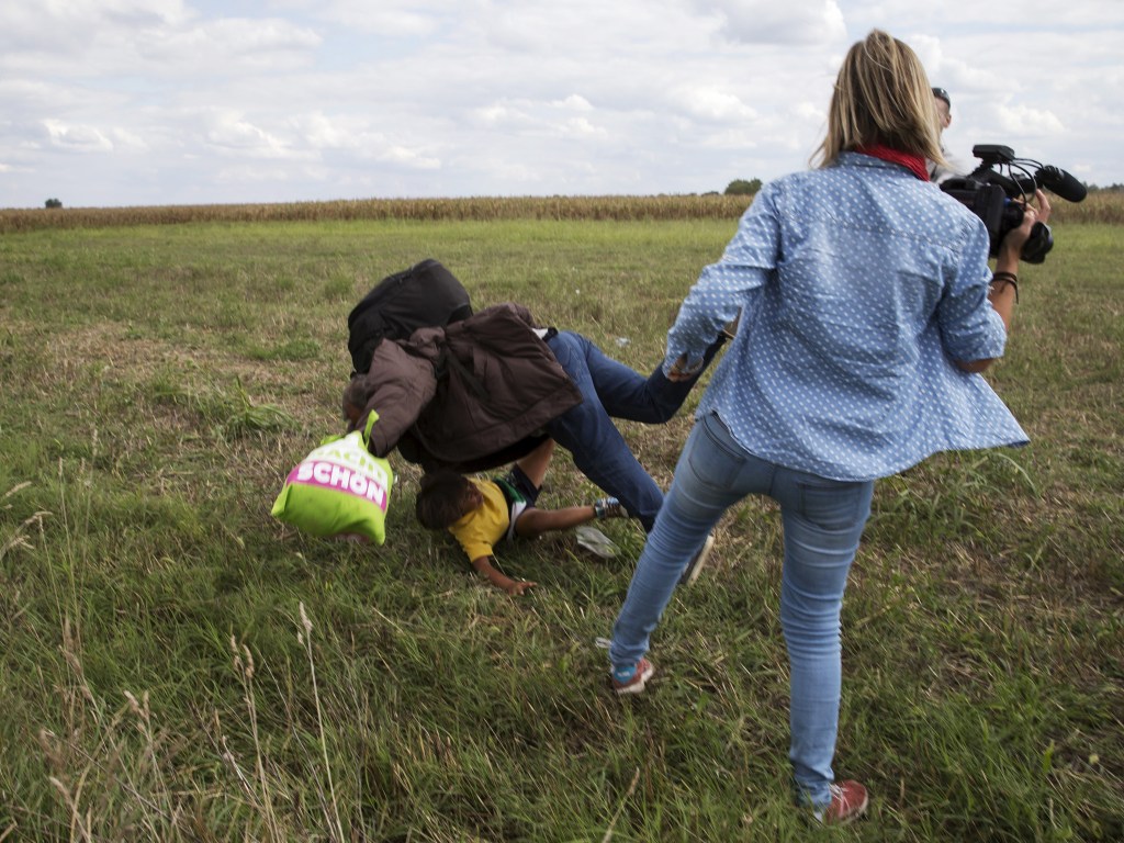 Homem refugiado com uma criança no colo é derrubado por uma cinegrafista enquanto tentavam fugir da polícia em Roszke, na Hungria - 08/09/2015