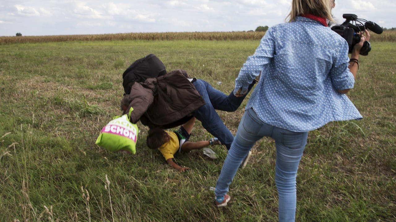 Homem refugiado com uma criança no colo é derrubado por uma cinegrafista enquanto tentavam fugir da polícia em Roszke, na Hungria - 08/09/2015