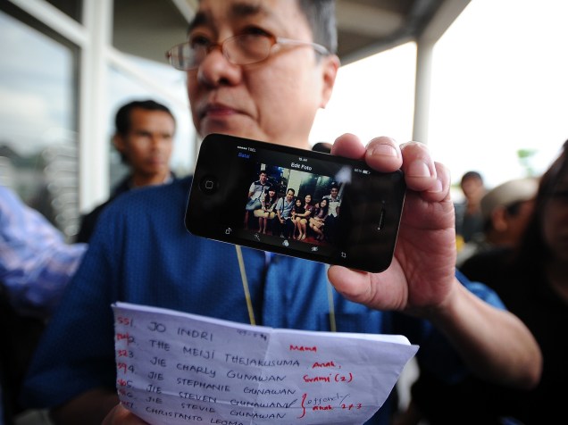 Homem exibe fotografia de seus familiares, vítimas do acidente aéreo com o voo QZ8501 da AirAsia em Surabaya, na Indonésia - 03/01/2015