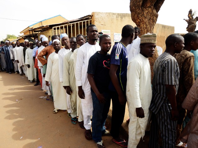 Homens esperam na fila do lado de fora de um local de votação em Daura, Nigéria - 28/03/2015