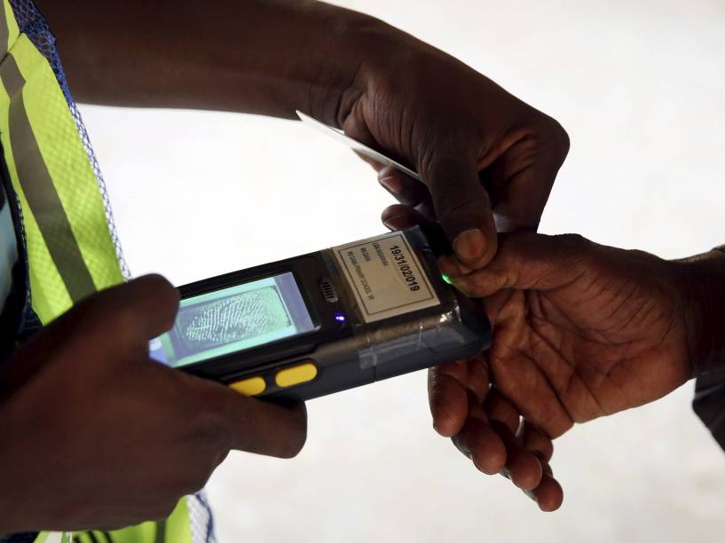 Integrante da comissão eleitoral confere a impressão digital de um eleitor em um posto de votação na cidade de Kano, Nigéria - 28/03/2015