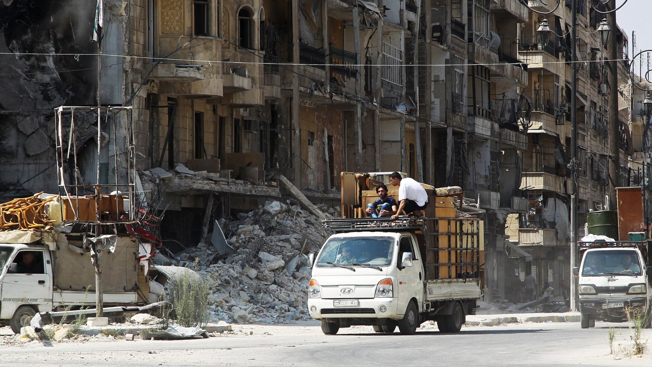 Homens carregam móveis em pequenos caminhões na cidade síria de Aleppo - 24/08/2015
