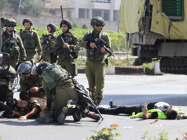Soldados israelenses socorre o companheiro ferido ao lado do corpo do palestino agressor