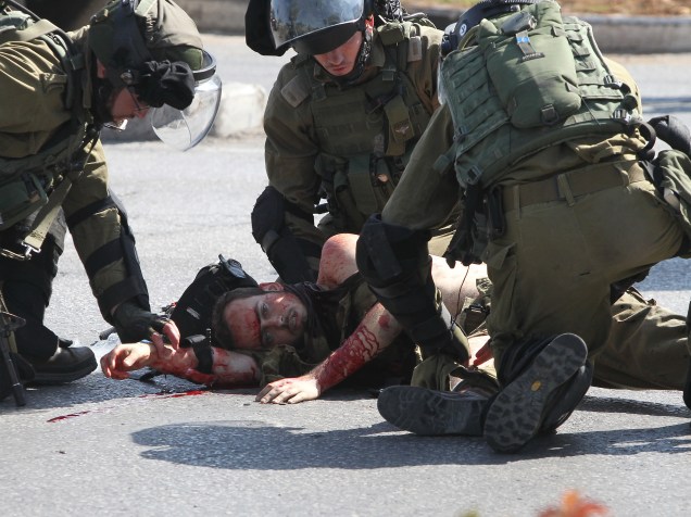 Soldados israelenses socorre o companheiro ferido ao lado do corpo do palestino agressor
