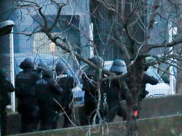 Fumaça é vista à esquerda de policiais que tentam entrar no supermercado onde várias pessoas são feitas reféns no leste de Paris