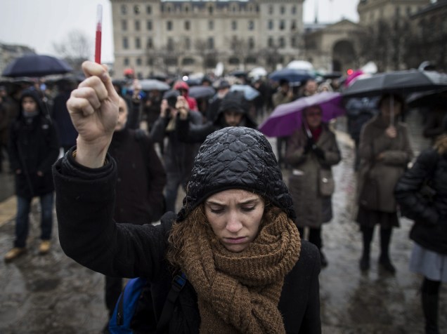 Mulher segura uma caneta durante um minuto de silêncio em frente à catedral de Notre Dame, em Paris, em memória das vítimas do ataque à redação da revista Charlie Hebdo - 08/01/2015