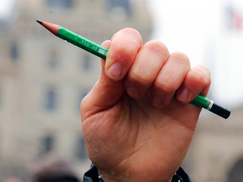 Homem ergue um lápis em frente à catedral de Notre Dame, em Paris, durante um minuto de silêncio por mortos no atentado