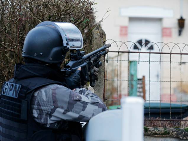 Membro da polícia francesa anti-terrorismo patrulha uma área em Corcy, a nordeste de Paris, onde os suspeitos do ataque à revista Charlie Hebdo foram vistos após roubar um posto de gasolina - 08/01/2015