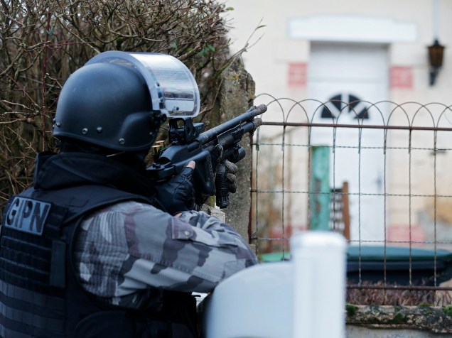 Membro da polícia francesa anti-terrorismo patrulha uma área em Corcy, a nordeste de Paris, onde os suspeitos do ataque à revista Charlie Hebdo foram vistos após roubar um posto de gasolina - 08/01/2015