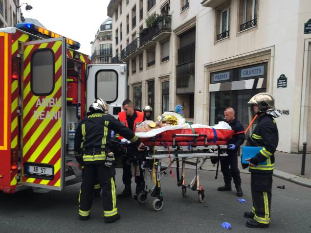 Bombeiros carregam um homem ferido em uma maca na frente dos escritórios do jornal satírico francês Charlie Hebdo em Paris, após o ataque de homens armados - 07/01/2015