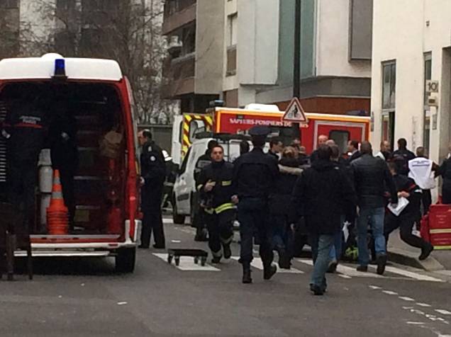 Policiais e bombeiros se reúnem em frente aos escritórios do jornal satírico francês Charlie Hebdo em Paris, depois de homens armados terem invadido o local - 07/01/2015