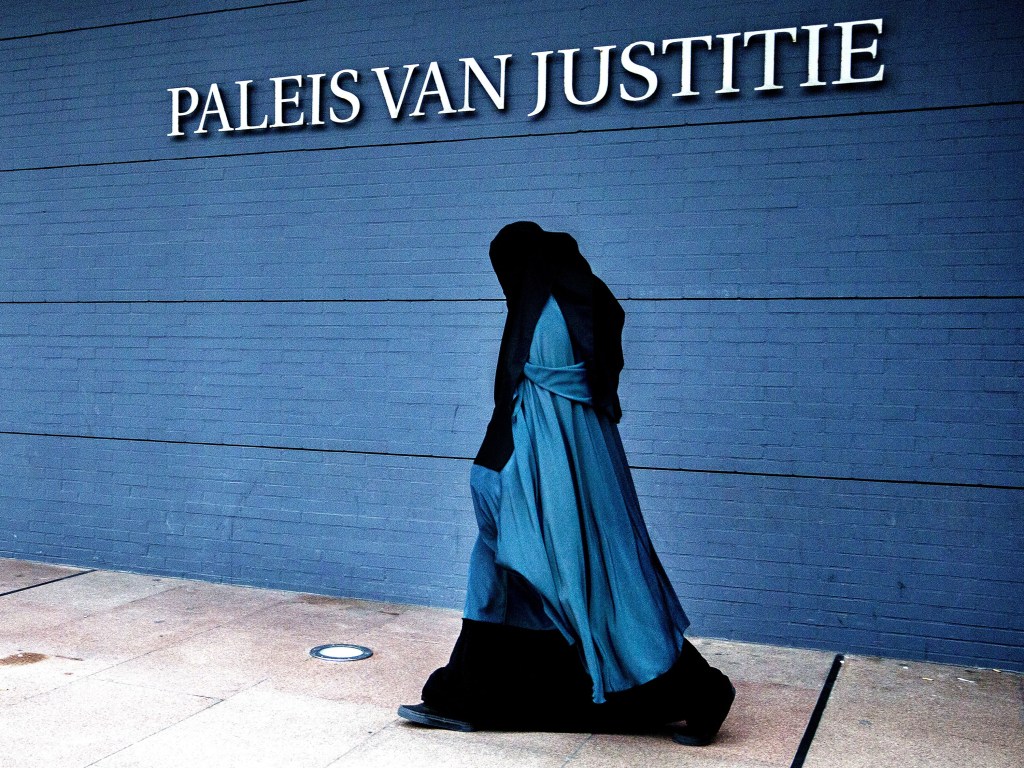 Mulher vestindo uma burca anda em frente ao Palácio da Justiça em Haia, na Holanda - 01/12/2004