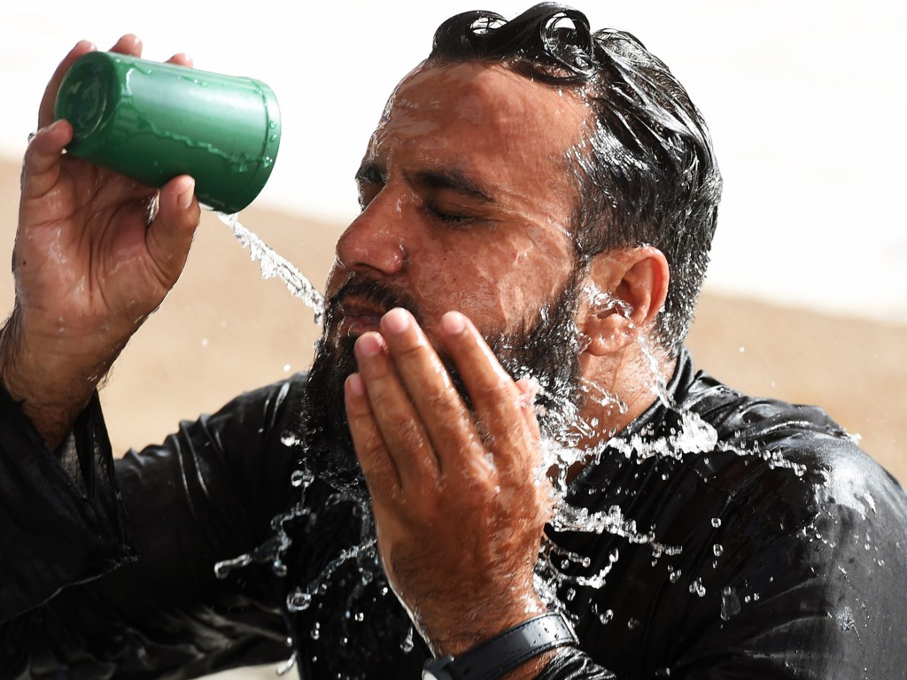 Homem se refresca com água no interior de uma mesquita durante uma onda de calor em Karachi, no Paquistão