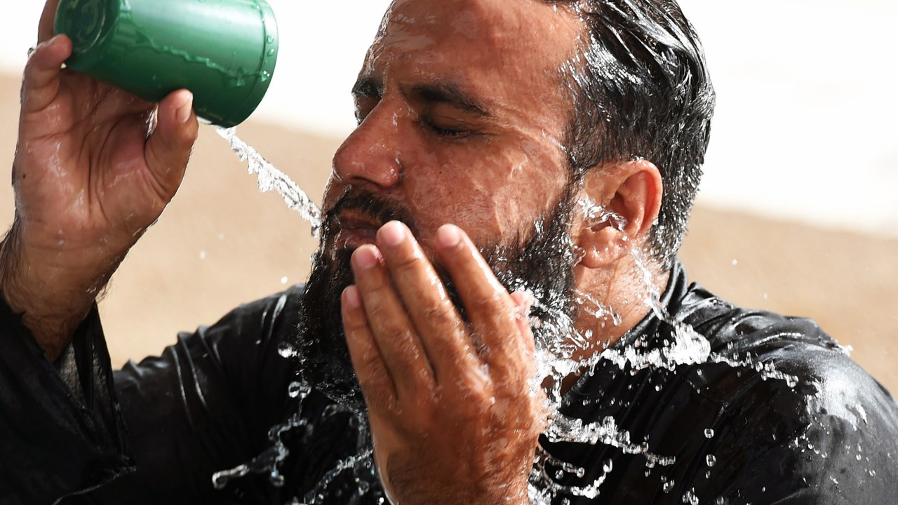 Homem se refresca com água no interior de uma mesquita durante uma onda de calor em Karachi, no Paquistão - 22/06/2015