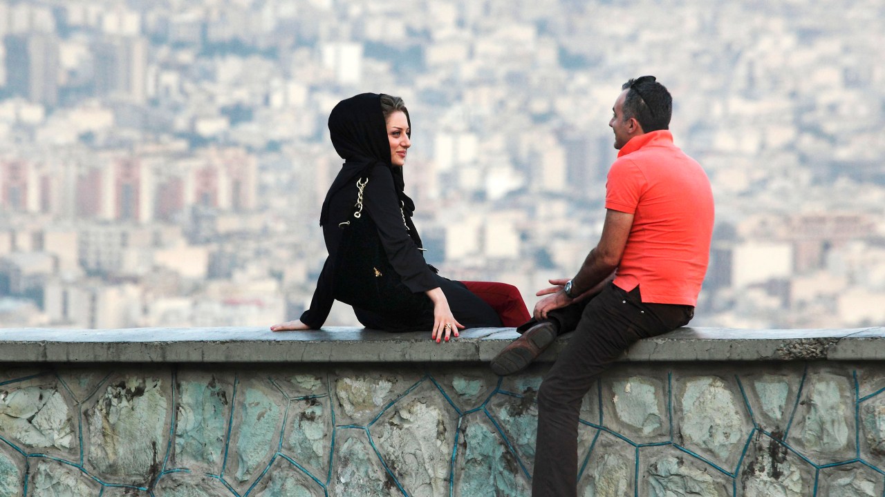 Jovem casal iraniano conversa em uma rua na capital Teerã
