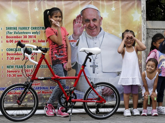 Crianças posam em frente a um pôster do papa Francisco em Manila, nas Filipinas. O pontífice visita o país e deve realizar uma missa na cidade de Tacloban, destruída pela passagem do tufão Hayan em 2013 - 14/01/2015