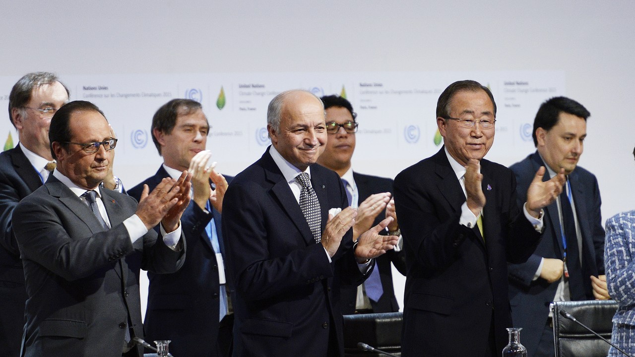 O presidente da França, François Hollande, o chanceler francês, Laurent Fabius e o secretário-geral da ONU, Ban Ki-Moon, aplaudem após anúncio da proposta final da Conferência do Clima (COP21) em Le Bourget, norte de Paris - 12/11/2015