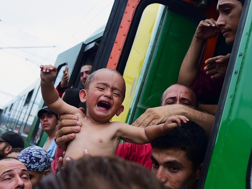 Refugiado segura um menino chorando do lado de fora de um trem que seguia para a fronteira com a Áustria, e foi parado em Bicske, na Hungria - 03/09/2015
