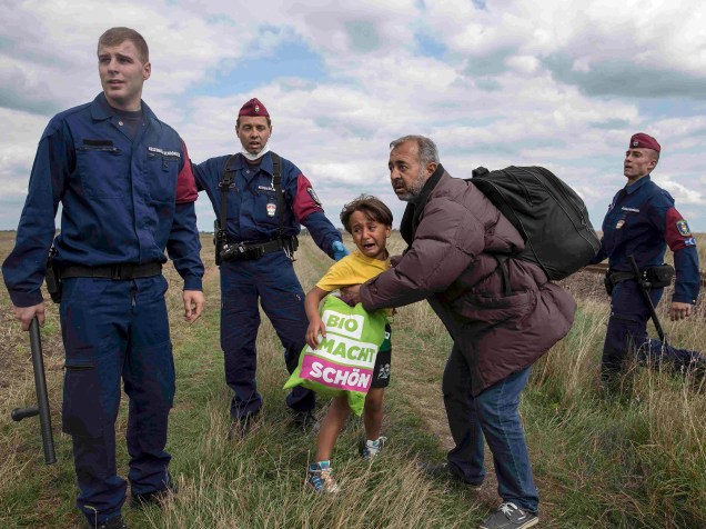 Criança chora ao ser detida pela polícia com o homem que a carregava enquanto tentavam atravessar a vila de Röszke, na Hungria - 08/09/2015
