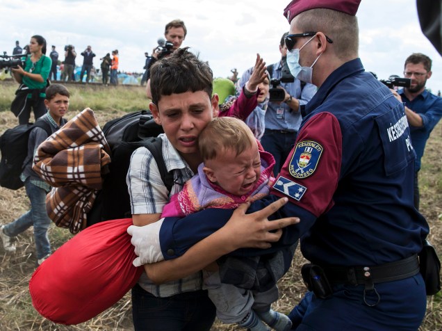 Policial tenta impedir a passagem de um menino refugiado com um bebê no colo na vila de Röszke, na Hungria - 08/09/2015
