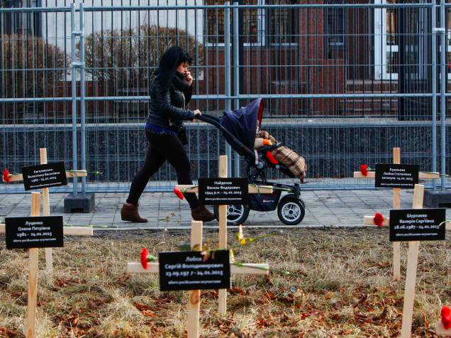 Mulher anda com carrinho de bebê em frente à cruzes postas no chão em homenagem aos mortos do bombardeio na cidade de Mariupol, Ucrânia, por combatentes pró-Rússia no último dia 24 de janeiro