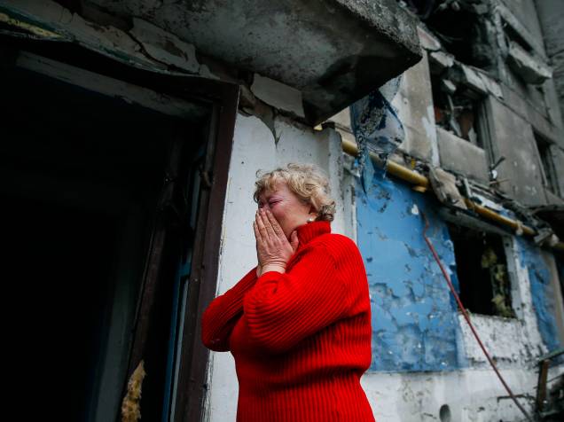 Mulher chora ao ver casas atingidas pelos bombardeios na cidade de Ienakiieve, na Ucrânia