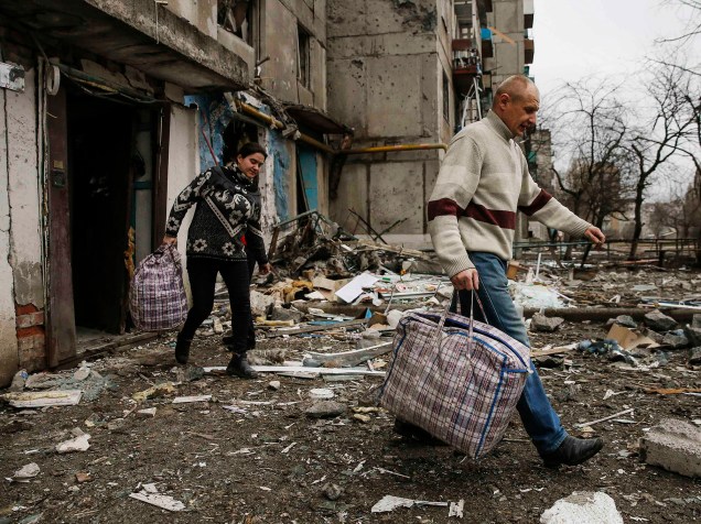 Moradores deixam suas casas após bombardeio na cidade de Ienakiieve, na Ucrânia