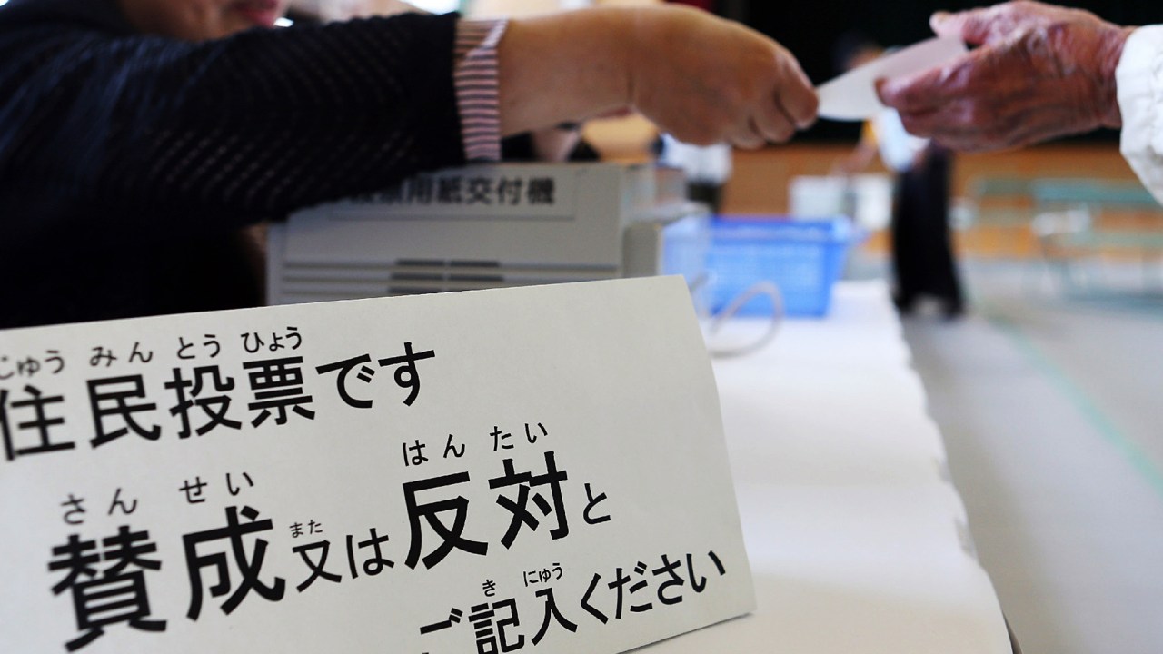 Cidadão recebe uma cédula em uma assembleia de voto em Osaka para votar em um referendo sobre a reforma da administração da cidade