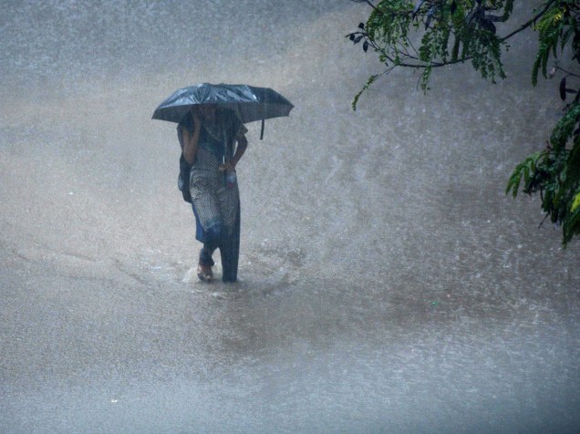 Mulher caminha com um guarda-chuva entre a enchente na cidade de Chennai no sul da Índia, durante uma chuva torrencial - 01/12/2015