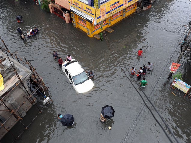 Carro fica coberto de água enquanto pessoas tentam empurrá-lo em meio a uma rua inundada na cidade de Chennai, no sul da Índia - 02/12/2015