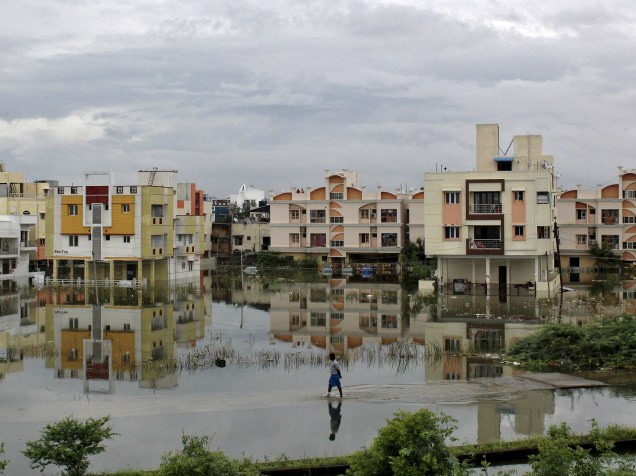 Homem anda através de uma área residencial inundada em Chennai, sul da Índia - 02/12/2015
