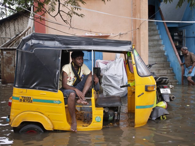 Momem senta em um riquixá em uma área inundada em Chennai, na Índia - 03/12/2015