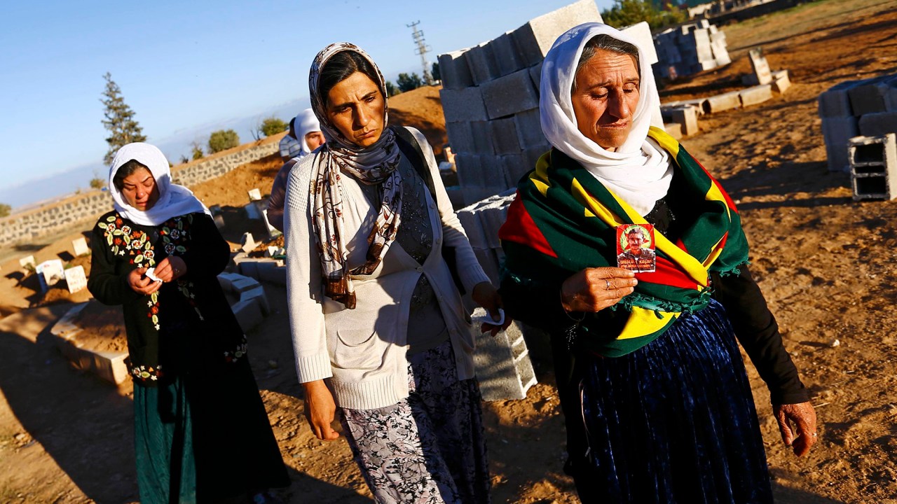 Mulheres curdas turcas chegam em um cemitério no sul de Suruc, na província de Sanliurfa, para o enterro de combatente curdo, morto em batalha contra o Estado Islâmico em Kobani, Síria