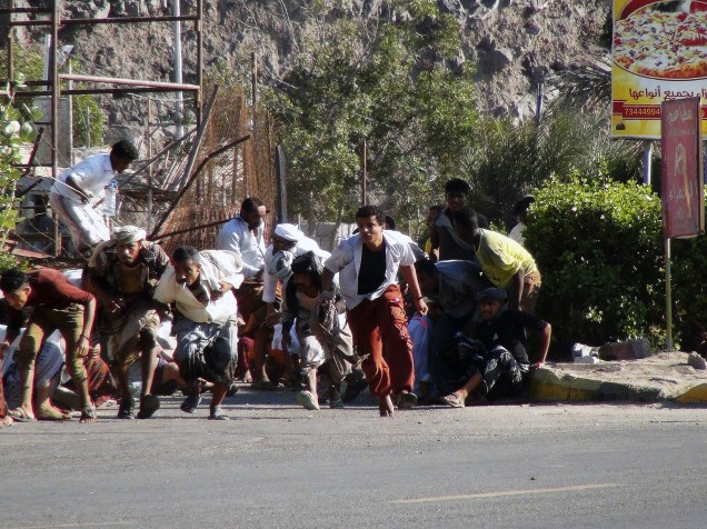 Pessoas procuram abrigo durante um tiroteio em uma base do exército na cidade portuária de Aden, no sul do Iêmen - 25/03/2015