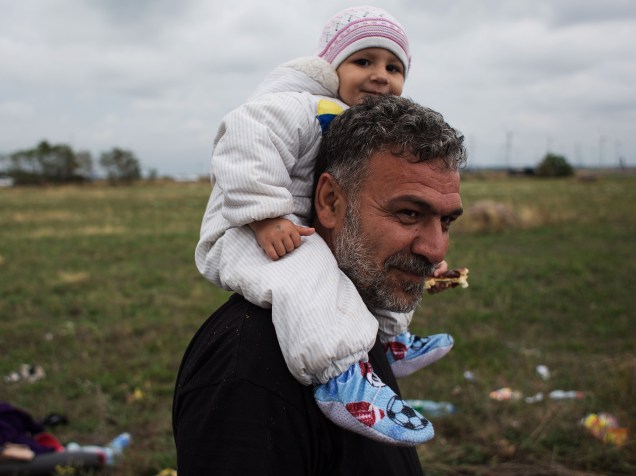 Refugiado carrega seu filho nos ombros enquanto caminha nos arredores da cidade austríaca de Nickelsdorf após cruzar a fronteira com a Hungria -  05/06/2015