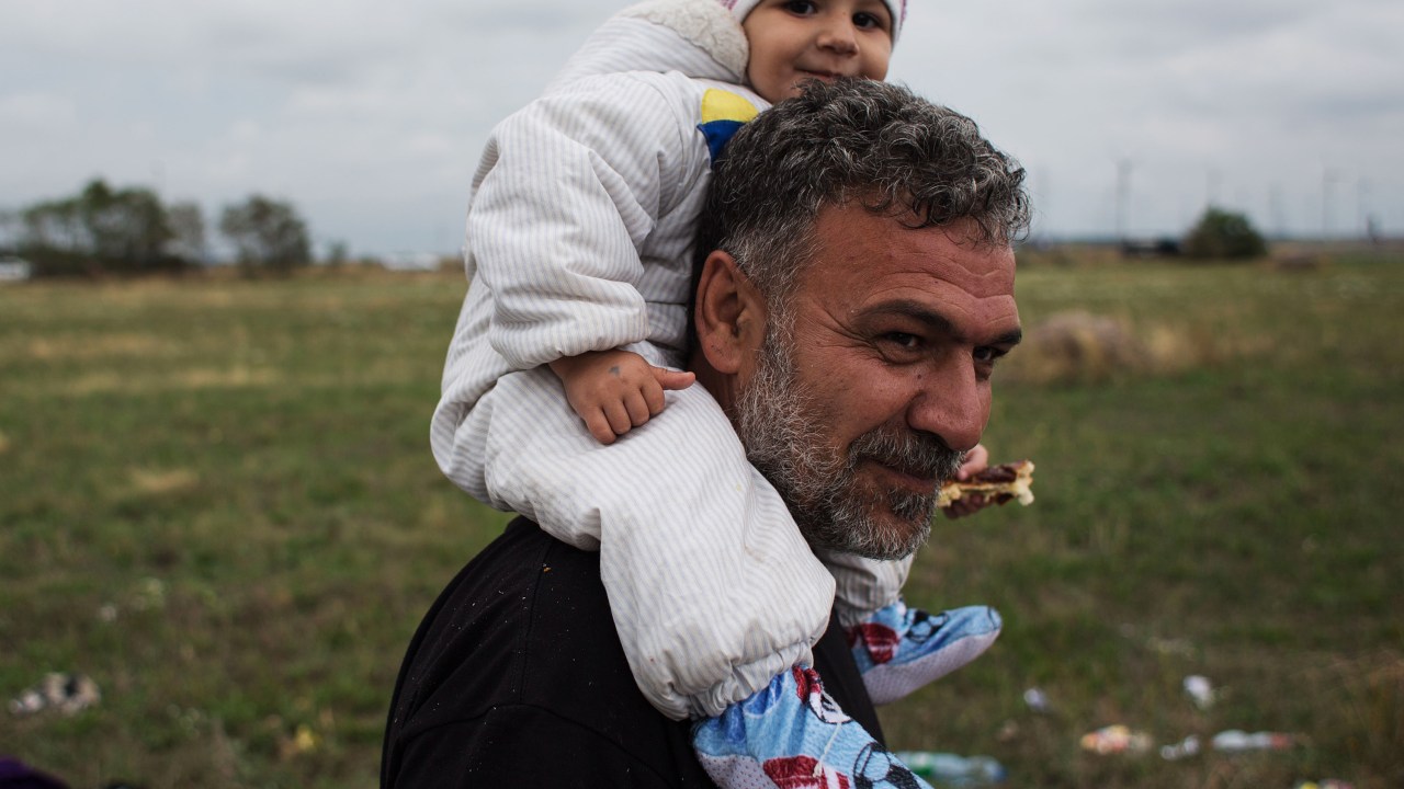 Refugiado carrega seu filho nos ombros enquanto caminha nos arredores da cidade austríaca de Nickelsdorf após cruzar a fronteira com a Hungria - 05/06/2015