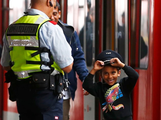 Menino refugiado brinca com o quepe de um oficial de segurança depois de desembarcar na principal estação de trem de Munique, na Alemanha - 05/09/2015