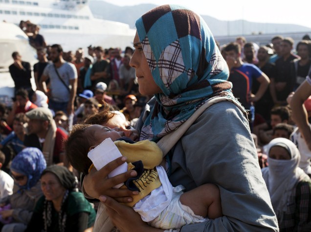 Mulher refugiada carrega dois bebês enquanto espera por um procedimento de registro no porto de Mitilene, na ilha grega de Lesbos - 05/09/2015