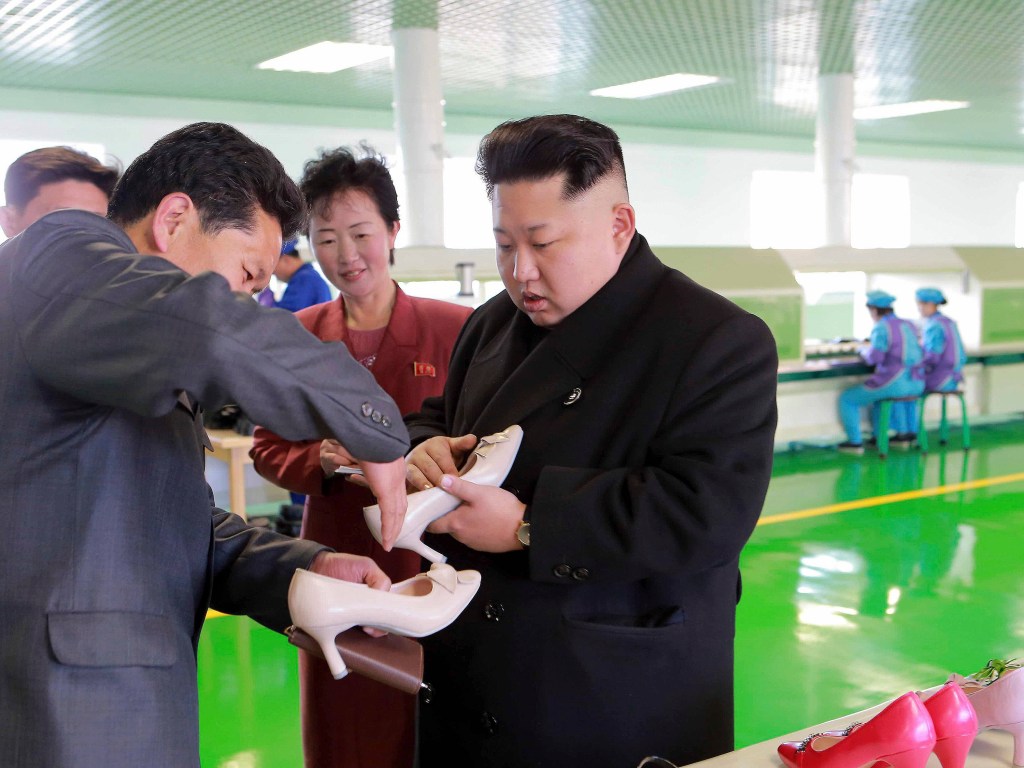 Ditador norte-coreano Kim Jong Un inspeciona um par de sapatos durante a sua visita a uma fábrica em Pyongyang