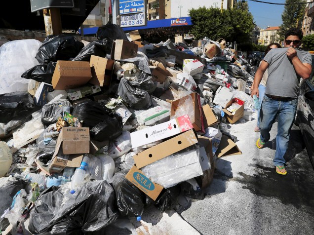 Homem cobre o nariz enquanto passa por uma pilha de lixo ao longo de uma rua em Beirute, no Líbano - 22/07/2015