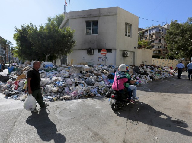 Pedestres caminham na rua para desviar do lixo acumulado na calçada em Beirute, no Líbano - 22/07/2015