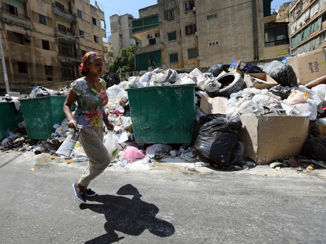 Mulher caminha através de uma montanha de lixo, polvilhada com pó de veneno para afastar ratos e insetos, em uma rua de Beirute, no Líbano - 23/07/2015