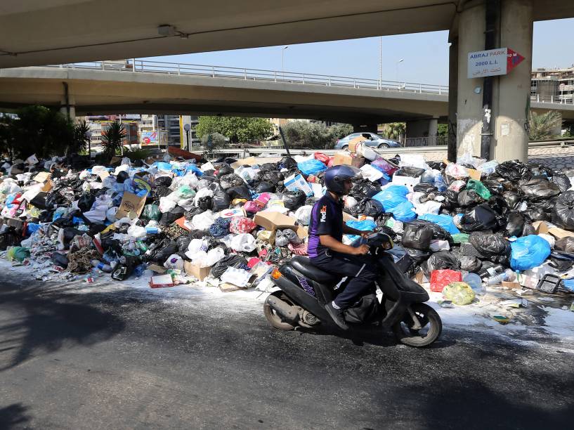 Motoqueiro passa diante de uma pilha de lixo acumulado em uma rua da cidade de Beirute, no Líbano - 23/07/2015