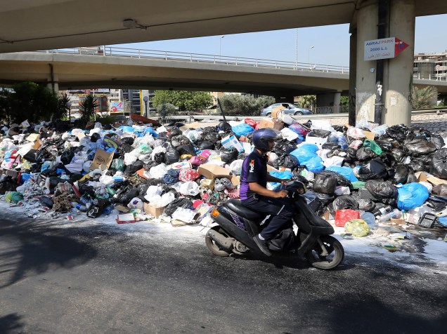 Motoqueiro passa diante de uma pilha de lixo acumulado em uma rua da cidade de Beirute, no Líbano - 23/07/2015