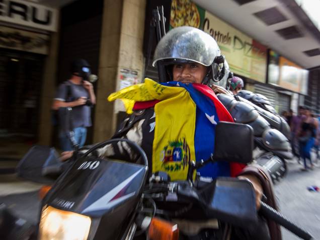Membro da Polícia Nacional Bolivariana carrega uma bandeira da Venezuela durante manifestação pelo aniversário da prisão do líder da oposição Leopoldo López em Caracas - 18/02/2015