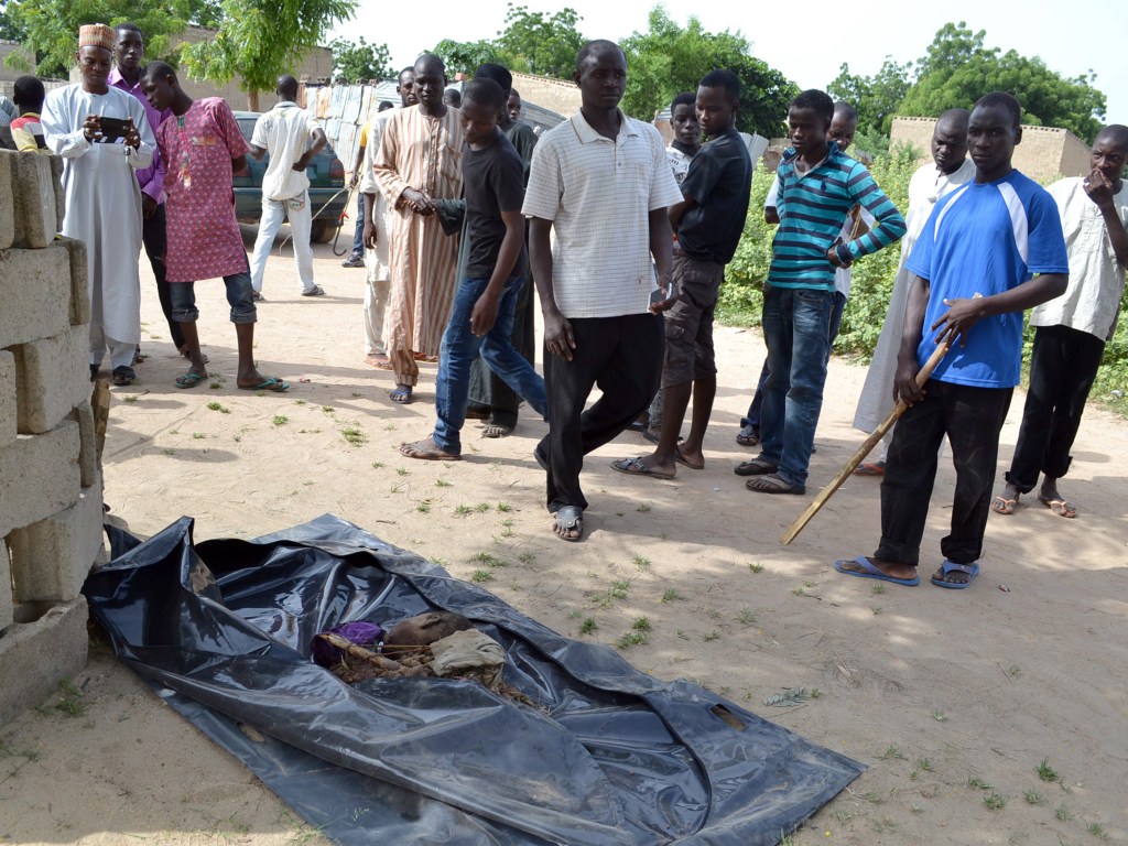 Populares olham para o corpo de um dos adolescentes suicidas que se explodiu durante ataque a bomba na cidade de Maiduguri, nordeste da Nigéria - 02/10/2015