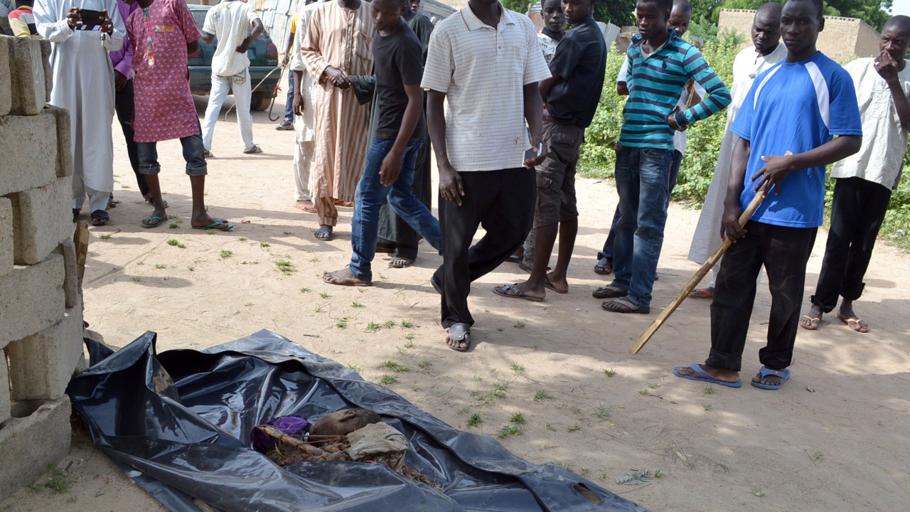 Populares olham para o corpo de um dos adolescentes suicidas que se explodiu durante ataque a bomba na cidade de Maiduguri, nordeste da Nigéria - 02/10/2015