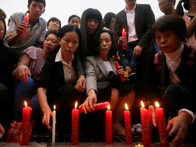 Pessoas acendem velas durante vigília em homenagem às vítimas do naufrágio no rio Yang Tsé